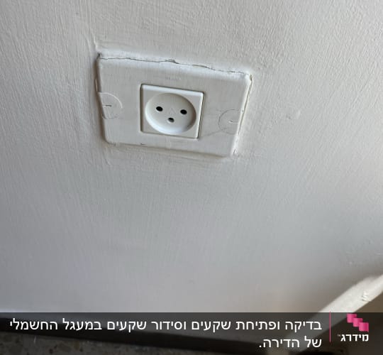 שקע חשמלי בקיר לבן עם רצפת אריחים